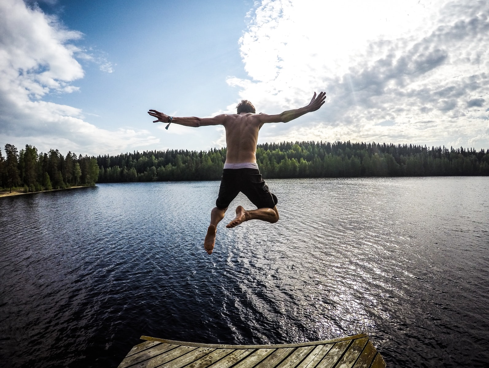 man jumping through body of water